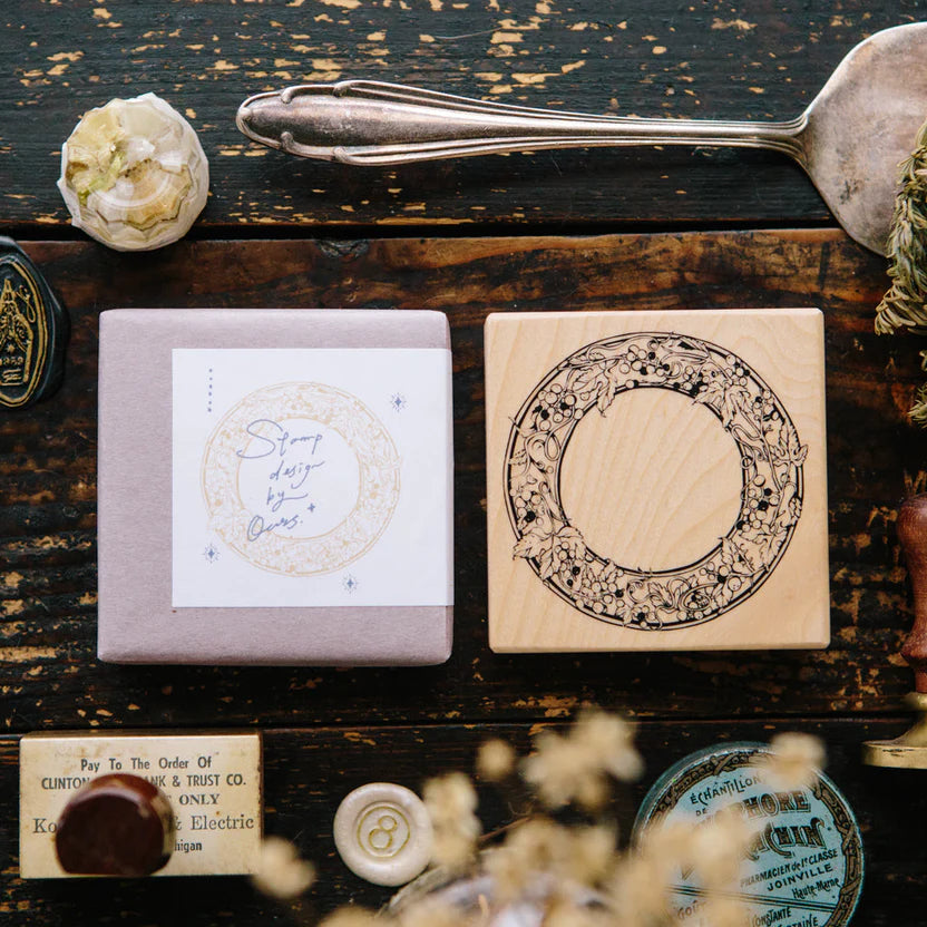 Wild Grape Frame Rubber Stamp styled among other stamps on a rustic wooden surface