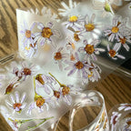 Sheet of floral stickers with white flowers and yellow centers on a clear background.