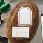Wooden board with printed arch shapes and a paintbrush on a rustic surface