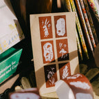 Card with printed designs held by a hand in a store setting