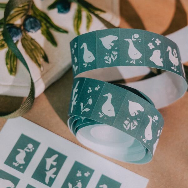 Roll of green tape with white duck designs on a wooden surface