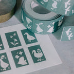 Green washi tape with white duck designs on a light gray surface.