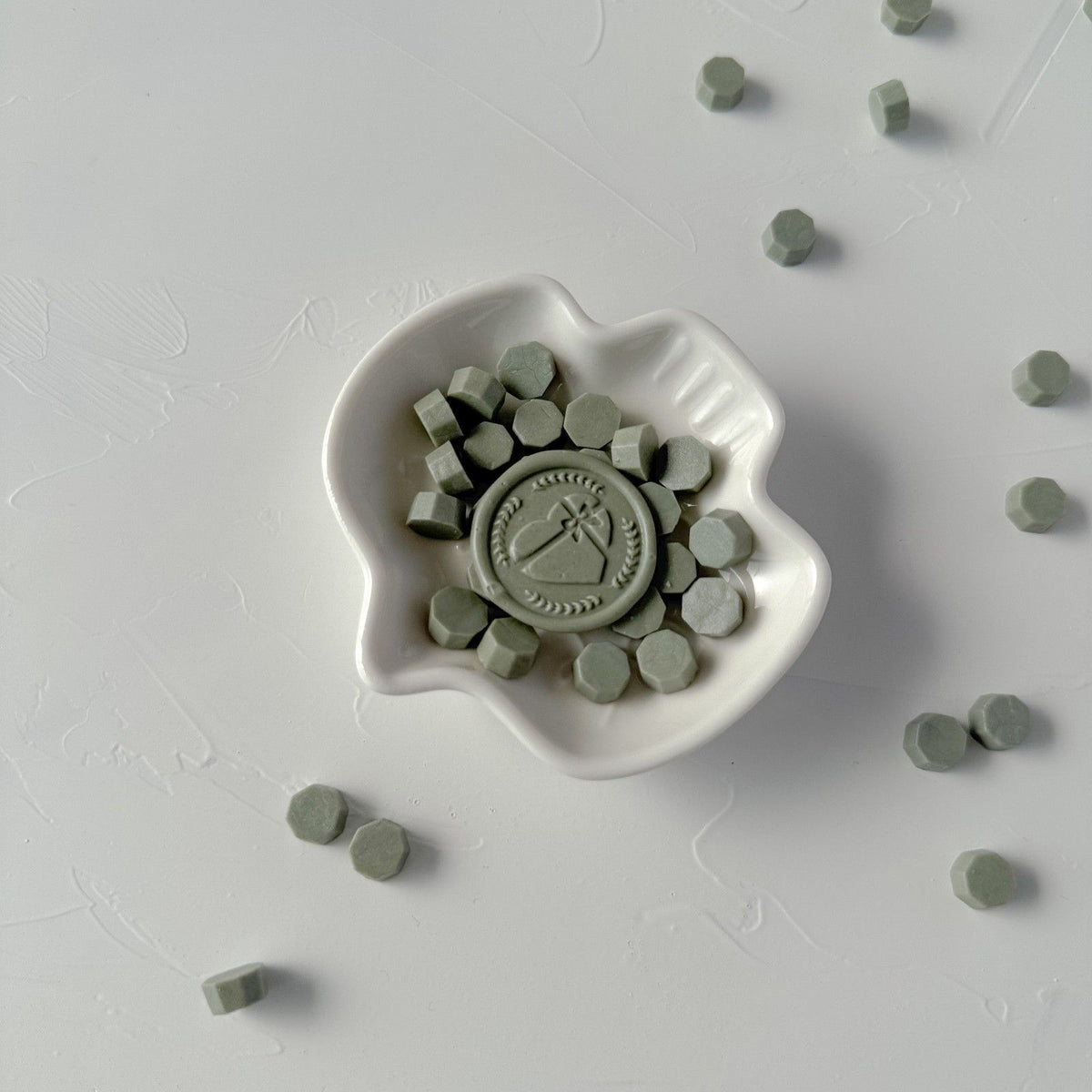 Woodlands Wax Beads in a white ceramic mold showing their hexagonal bead shape on a light grey backdrop