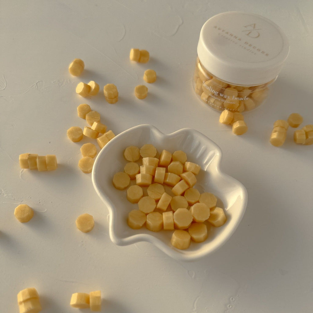 Yellow candy pieces in a white bowl on a light gray background with a container labeled 'M.'