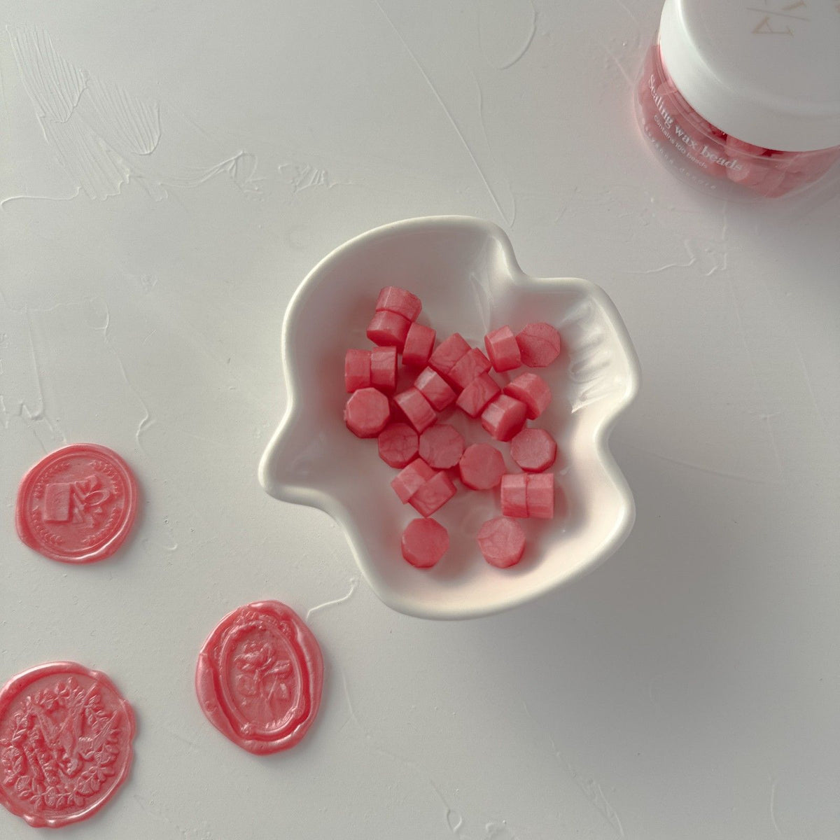 Young Wine sealing wax bead pieces arranged in a white heart-shaped dish on a bright white backdrop
