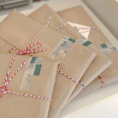 Vintage-style journals wrapped in kraft paper and tied with red twine, arranged as aesthetic stationery gift set