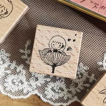 Wooden stamp with a design of a girl holding an umbrella on a textured surface.