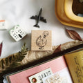 Wooden stamp with a design of a person holding a globe on a surface with stationery items.