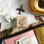 Wooden stamp with a design of a person holding a globe on a surface with stationery items.