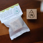 Tea bag, rubber stamp with bear design, and card on a wooden surface