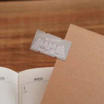 Winter Label Sticker Tape by Ivy Snow embossed label on an open notebook on a wooden desk