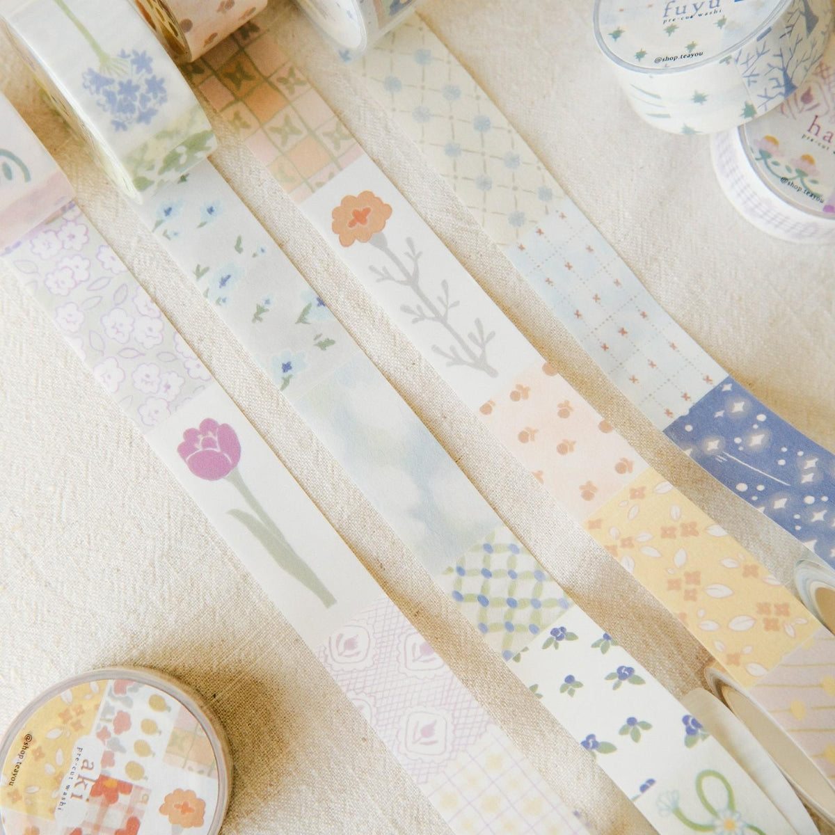 Set of decorative washi tape rolls with floral and nature-themed designs on a light background.