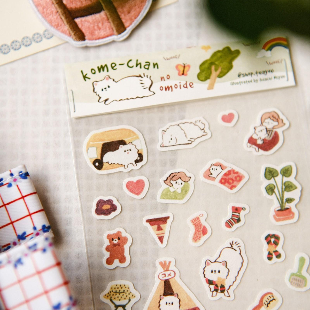 Collection of cute illustrated stickers on a textured surface with a small book titled 'kome-chan no omoide'.