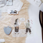Illustrated characters on a textured surface with a sewing machine in the background