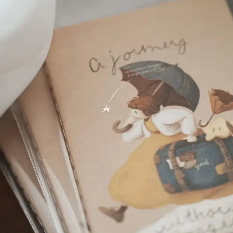 Notebook with a cute illustration of a bear holding an umbrella and a suitcase, with text 'A journey' on a beige background.
