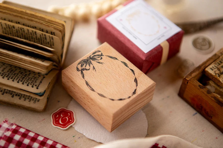 Wooden stamp with a design on a textured surface with books and a small box.