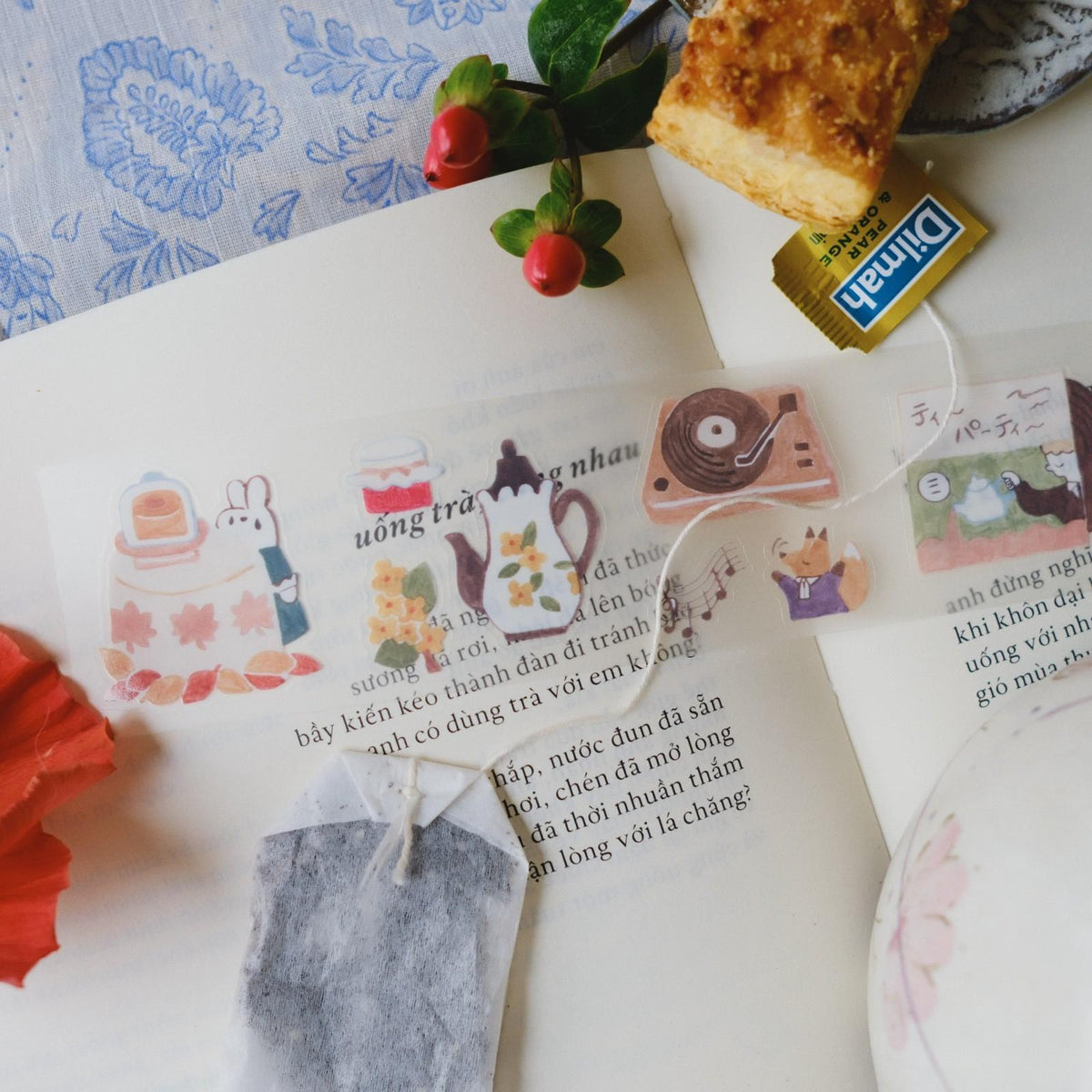 Open book with decorative stickers and a tea bag on a table.