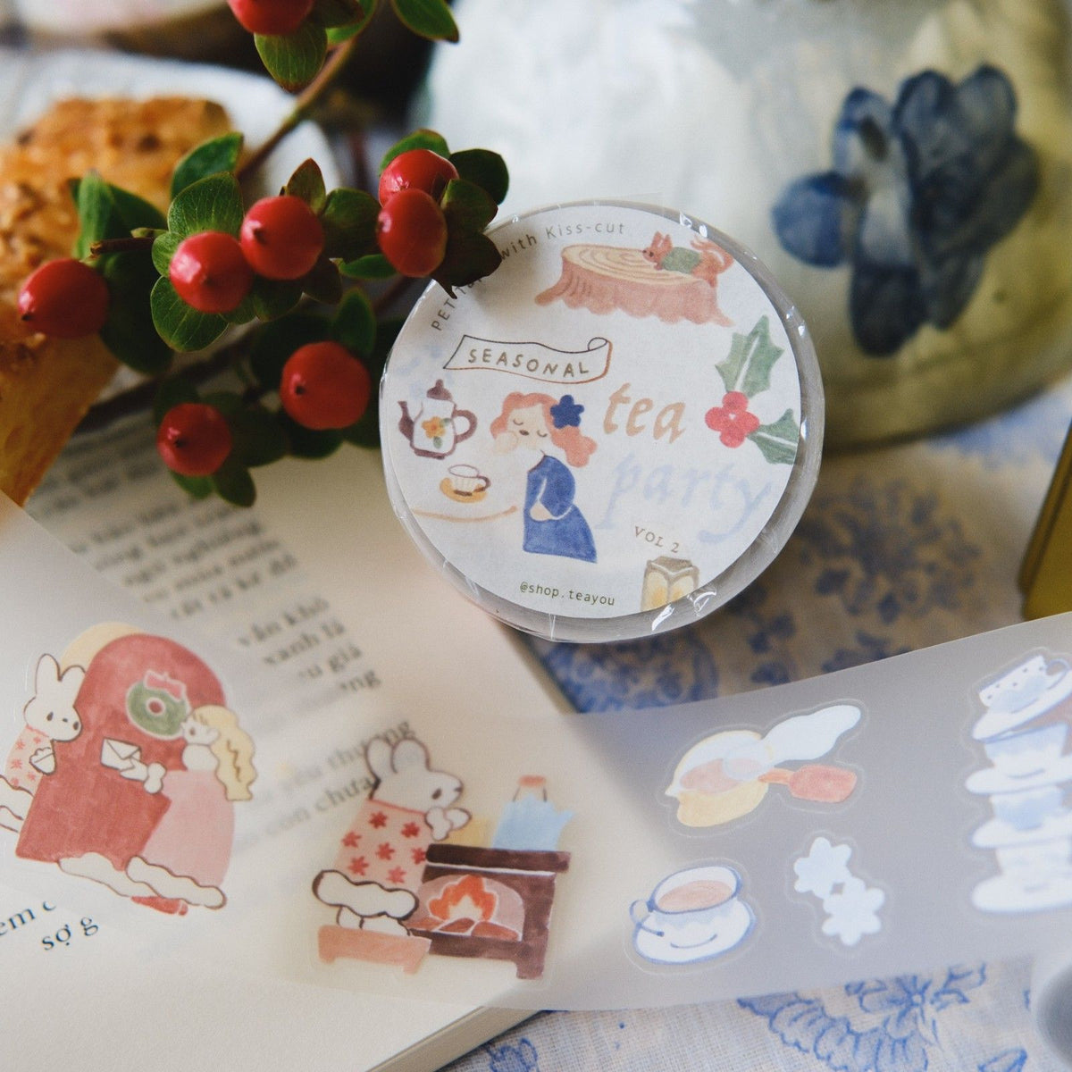 Sticker sheet with tea-themed designs on a surface with berries and a teapot.
